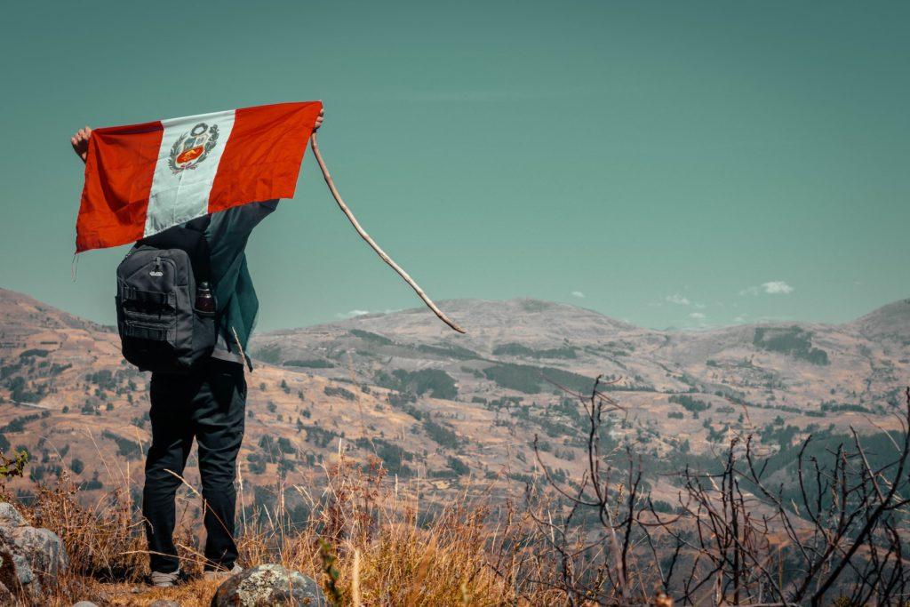 man carrying flag on top of cliff